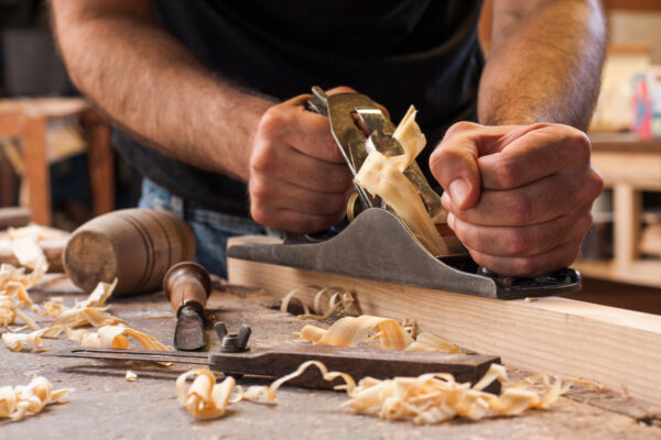 carpenter working with plane on wooden background